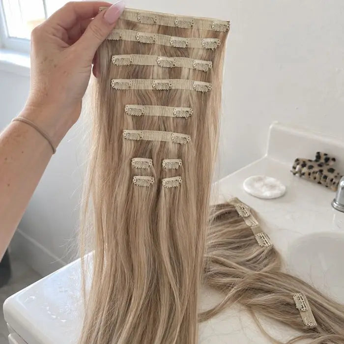Blonde hair extensions held over a bathroom counter